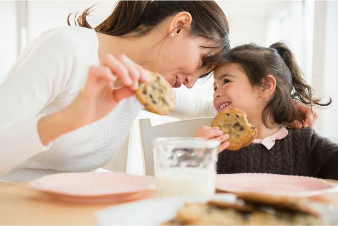 Woman and little girl eating cookies with milk 