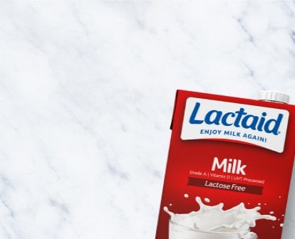 Box of Lactaid lactose-free shelf stable milk on a countertop next to a bowl of cereal and berries