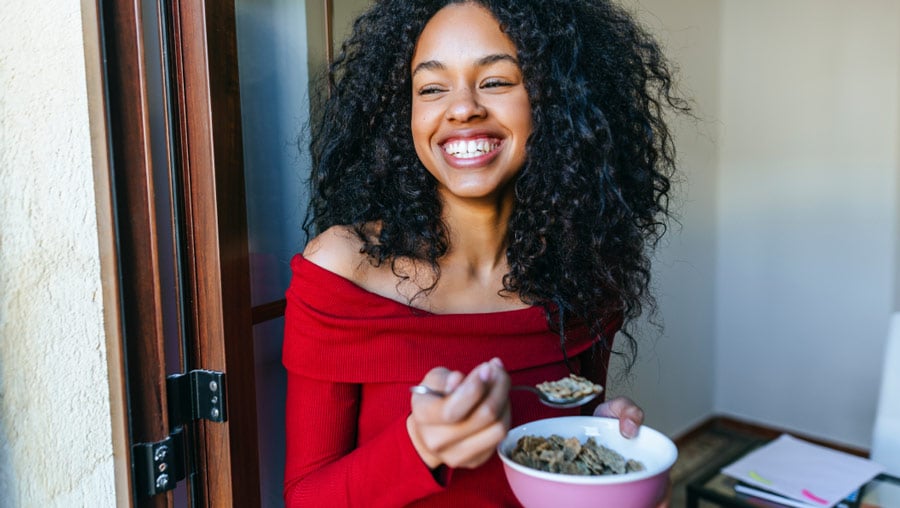 Woman smiling as she eats a bowl of cereal