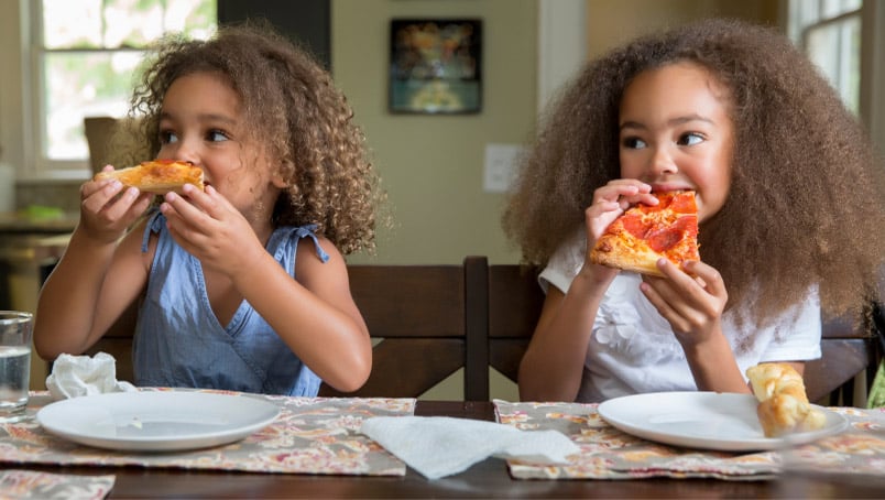 Two little girls eating pizza
