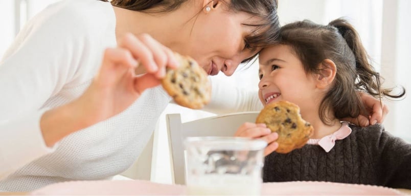 A woman and a little girl enjoying cookies together.