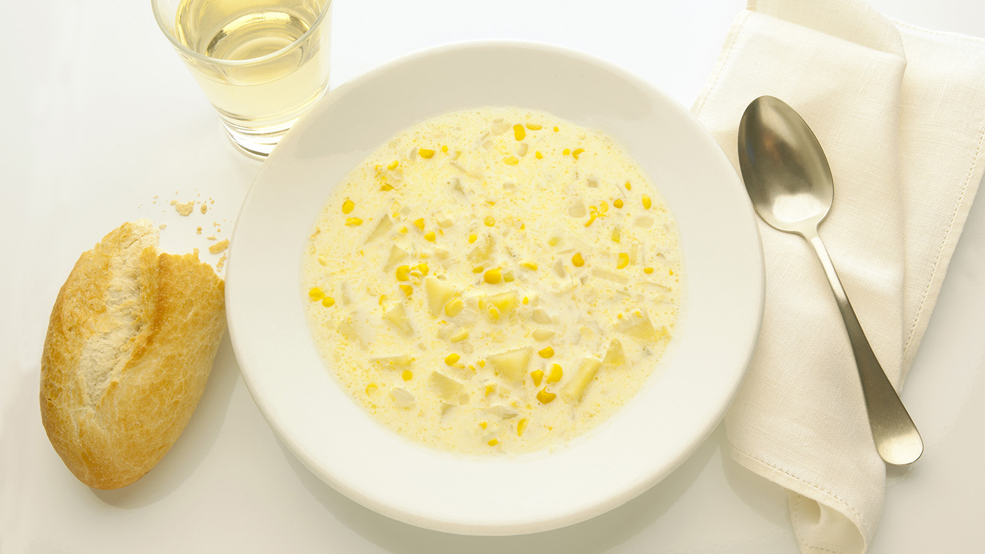 Corn chowder soup bowl with bread and wine