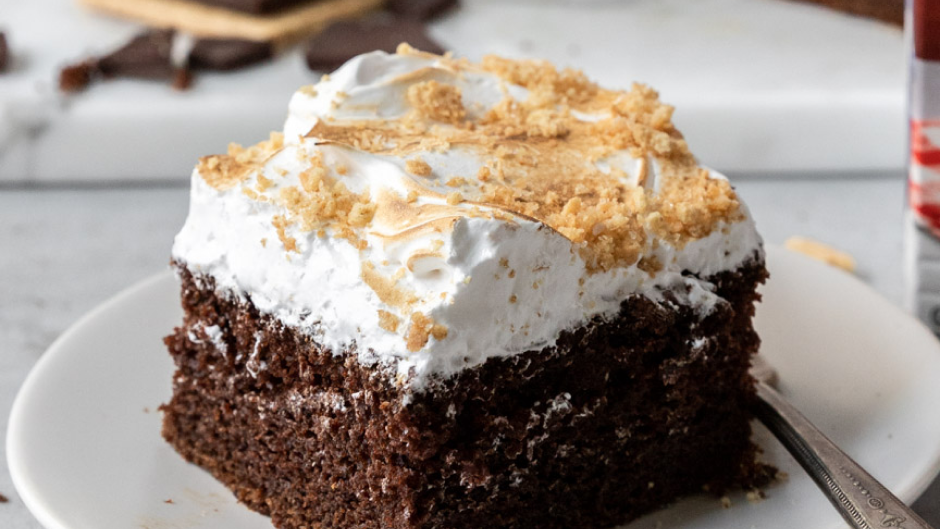 Smores flavored cake topped with marshmallow icing and graham cracker crumbles