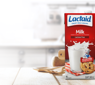 Box of Lactaid lactose-free shelf stable milk on a countertop next to a bowl of cereal and berries