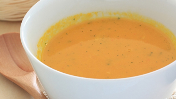 Autumn pumpkin soup in white bowl and wooden spoon