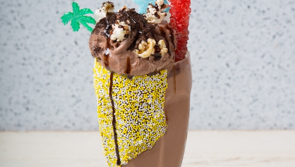 Decorated art chocolate milkshake with candy, popcorn, and sprinkles