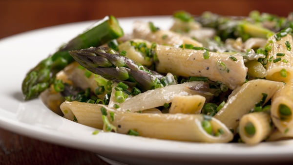 Close up of creamy lactose-free penne pasta with chives and asparagus