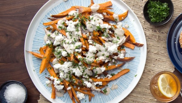 Loaded sweet potato fries with cheese and parsley with an iced tea